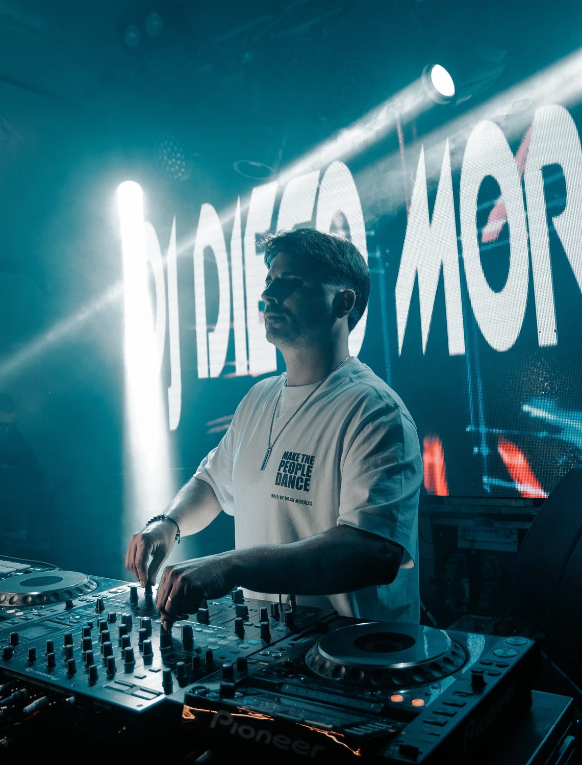 DJ Diego Morales na cabine, com o seu nome no ecrã LED